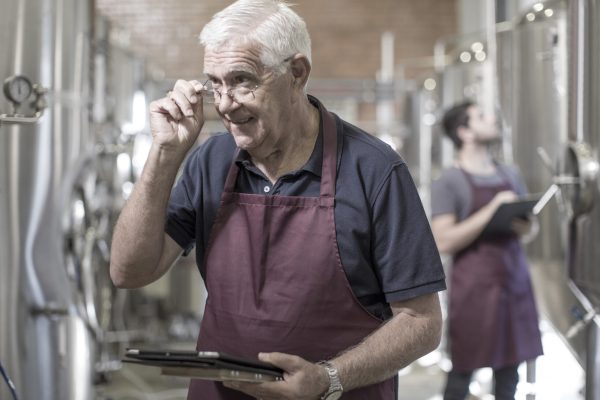 Brewers in brewery standing next to stainless steel tanks