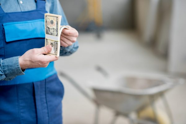 Builder counting his salary at the construction site. Close-up view focused on the money